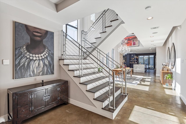 stairway with concrete floors, an inviting chandelier, and plenty of natural light