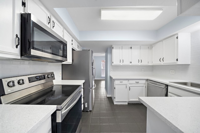 kitchen featuring dark tile patterned floors, sink, white cabinetry, and stainless steel appliances