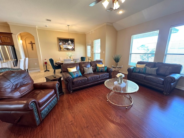 living room with wood-type flooring, vaulted ceiling, ceiling fan, and ornamental molding