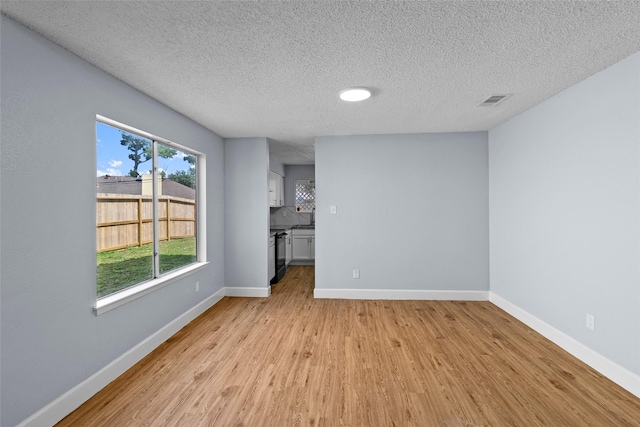 unfurnished living room with light hardwood / wood-style floors and a textured ceiling