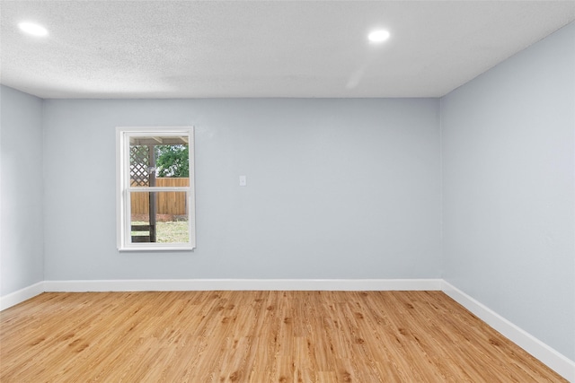 spare room featuring a textured ceiling and light wood-type flooring