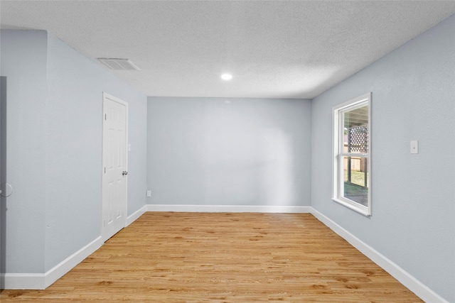 spare room with a textured ceiling and light hardwood / wood-style flooring