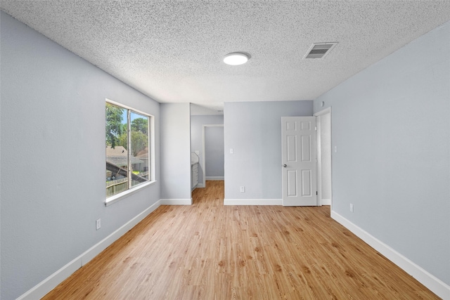 unfurnished room featuring a textured ceiling and light wood-type flooring