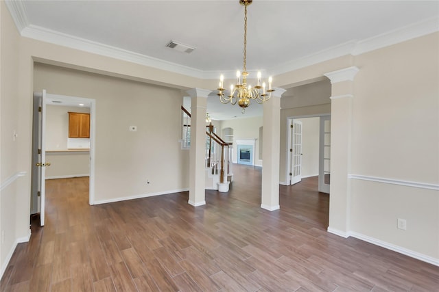 unfurnished dining area with wood-type flooring, an inviting chandelier, and crown molding