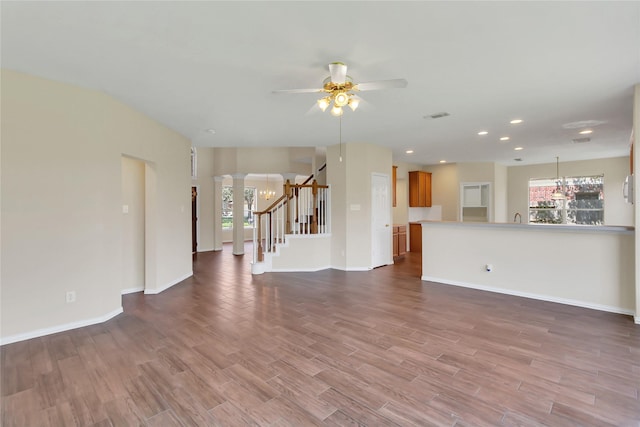 unfurnished living room featuring ceiling fan, wood-type flooring, and decorative columns