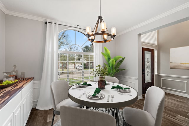 dining area with dark hardwood / wood-style floors, ornamental molding, and an inviting chandelier