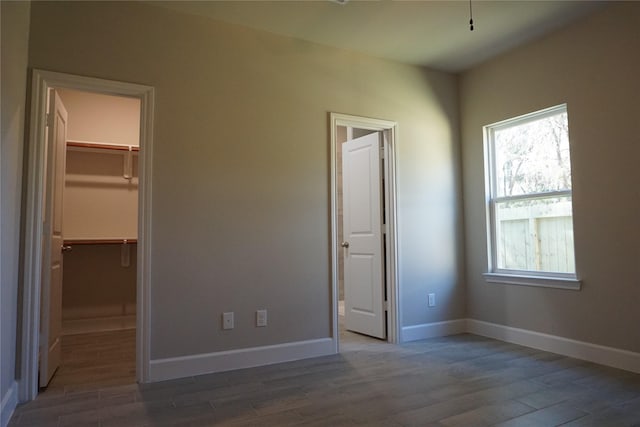 unfurnished bedroom with a walk in closet, dark hardwood / wood-style floors, and a closet