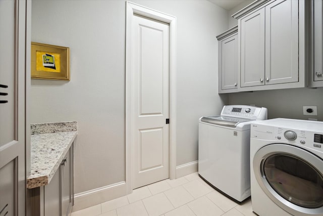 clothes washing area with light tile patterned flooring, separate washer and dryer, and cabinets