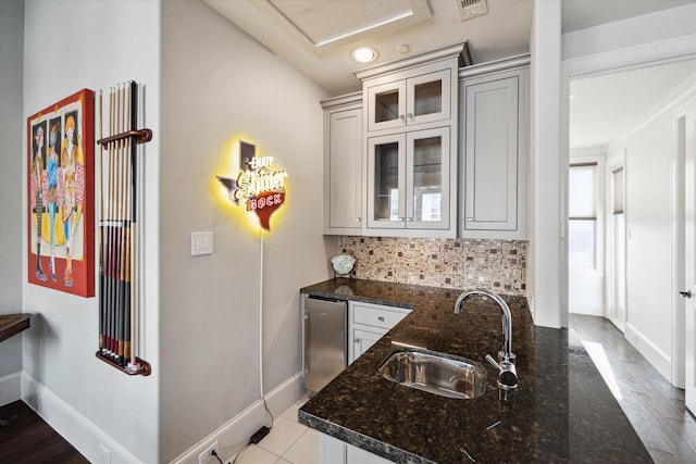 kitchen with dark stone counters, refrigerator, sink, light tile patterned flooring, and tasteful backsplash