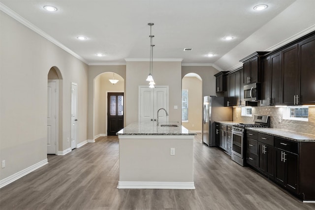 kitchen with light stone countertops, appliances with stainless steel finishes, sink, a center island with sink, and decorative light fixtures