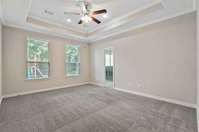 carpeted empty room featuring ceiling fan, ornamental molding, and a tray ceiling