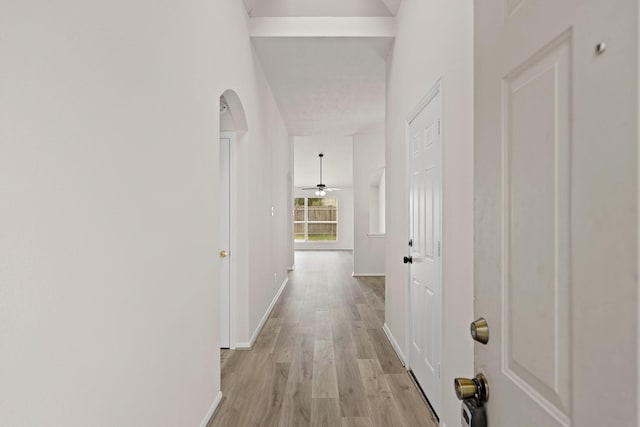 hallway with a towering ceiling and light hardwood / wood-style floors