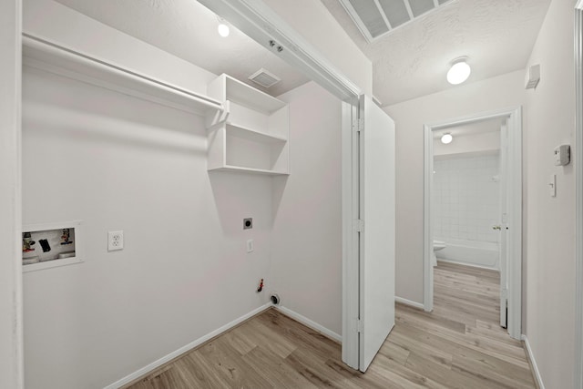 clothes washing area with light hardwood / wood-style floors, hookup for a washing machine, a textured ceiling, and hookup for an electric dryer