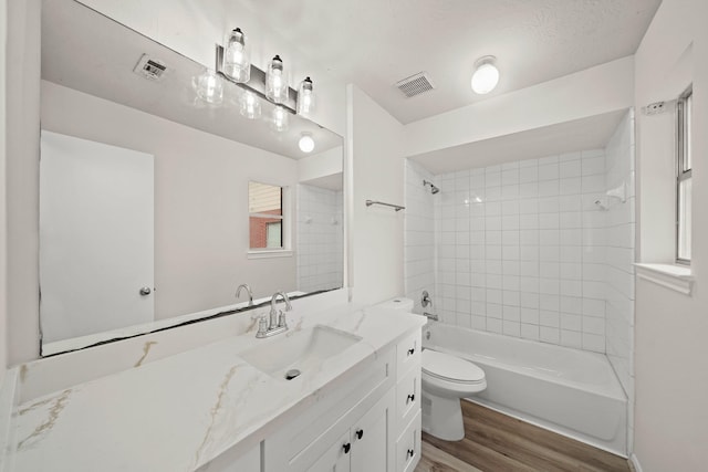 full bathroom featuring toilet, hardwood / wood-style flooring, tiled shower / bath, and vanity