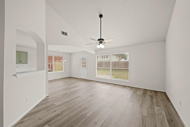 unfurnished living room featuring vaulted ceiling, ceiling fan, light hardwood / wood-style flooring, and a wealth of natural light