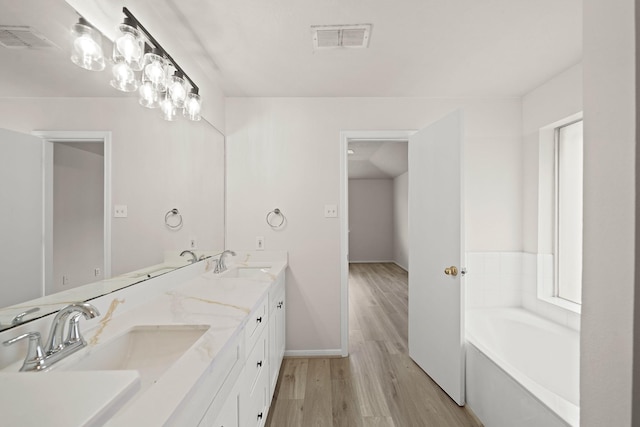 bathroom with hardwood / wood-style floors, a tub to relax in, and vanity