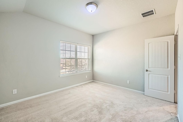 spare room featuring light colored carpet and lofted ceiling