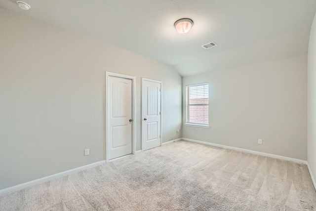 unfurnished bedroom featuring light colored carpet and lofted ceiling