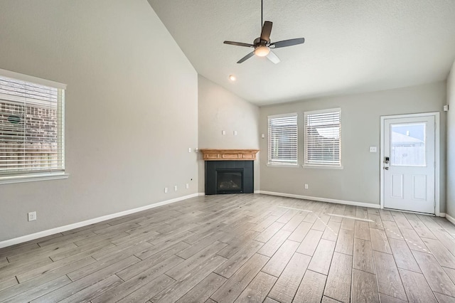 unfurnished living room featuring a textured ceiling, light hardwood / wood-style floors, ceiling fan, and lofted ceiling