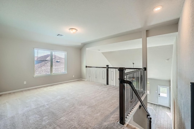 spare room featuring light colored carpet and lofted ceiling