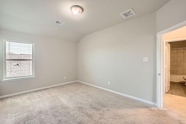 carpeted empty room with a textured ceiling and vaulted ceiling