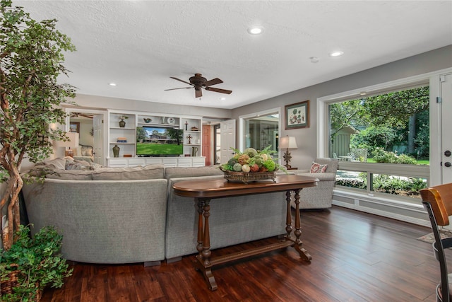 living room with a textured ceiling, ceiling fan, plenty of natural light, and dark hardwood / wood-style floors