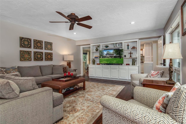 living room with dark hardwood / wood-style flooring, a textured ceiling, and ceiling fan