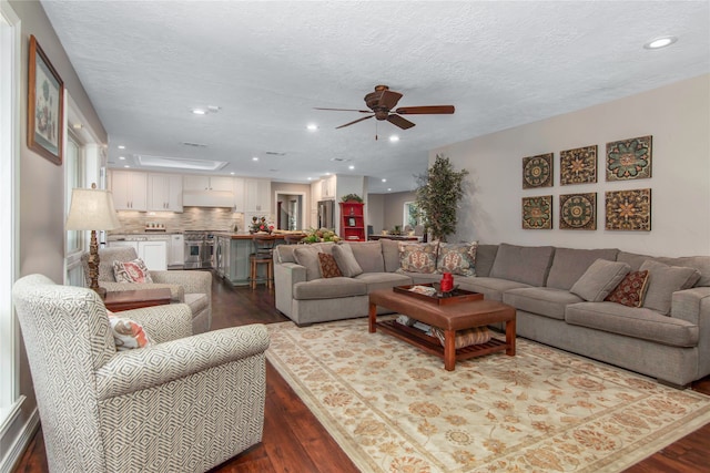 living room featuring a textured ceiling, hardwood / wood-style flooring, and ceiling fan