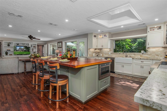 kitchen featuring white cabinets, sink, ceiling fan, butcher block countertops, and a kitchen island