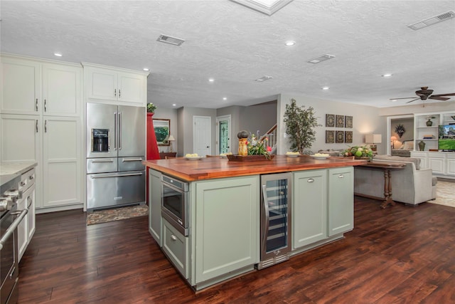 kitchen with white cabinets, wine cooler, ceiling fan, appliances with stainless steel finishes, and butcher block countertops