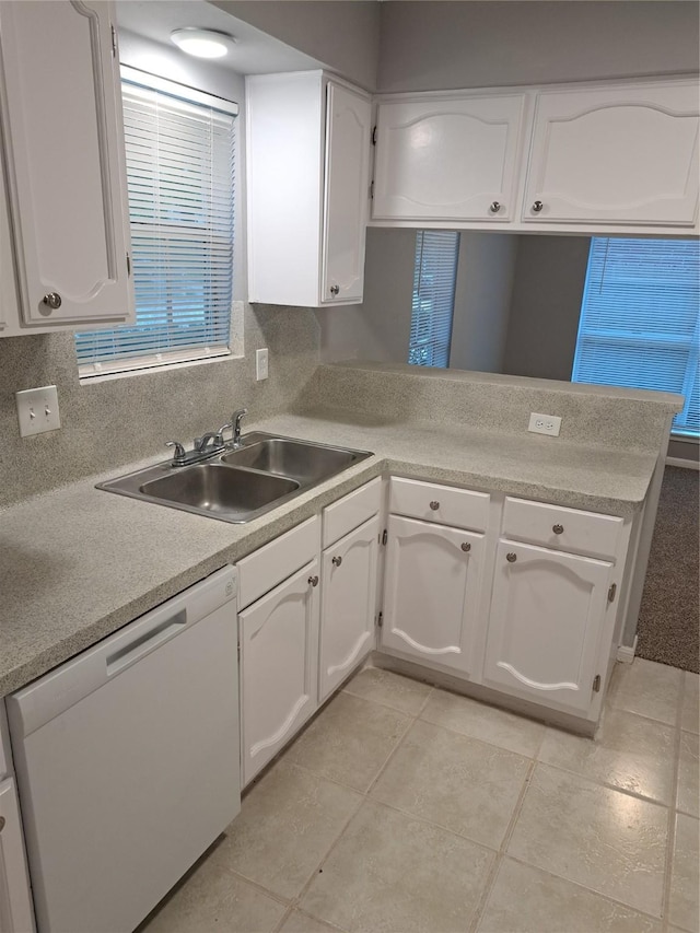 kitchen with kitchen peninsula, dishwasher, white cabinets, and sink