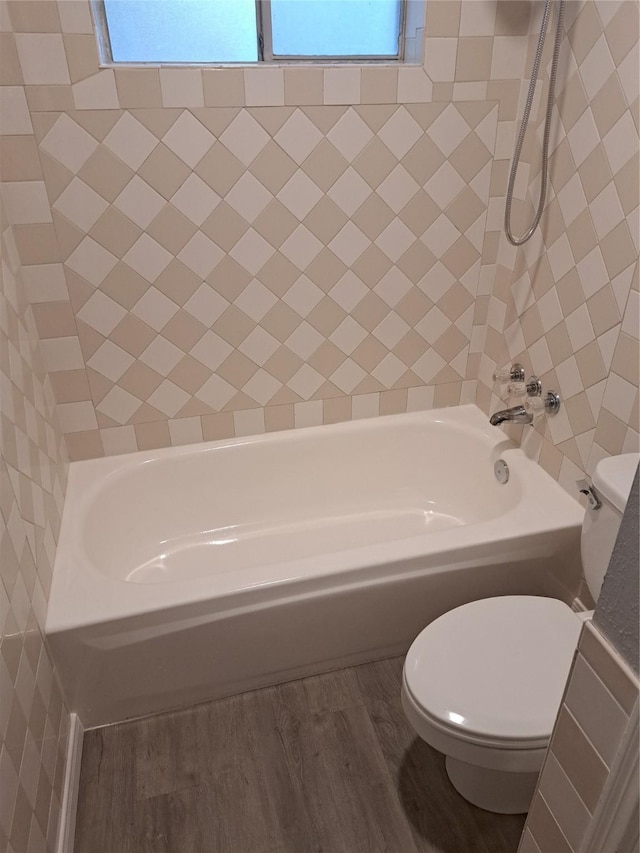 bathroom with tiled shower / bath, wood-type flooring, and toilet