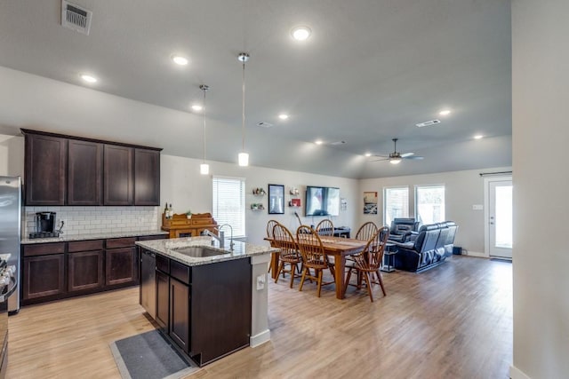 kitchen featuring ceiling fan, a kitchen island with sink, sink, decorative light fixtures, and lofted ceiling