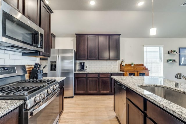 kitchen with backsplash, light stone countertops, decorative light fixtures, and appliances with stainless steel finishes