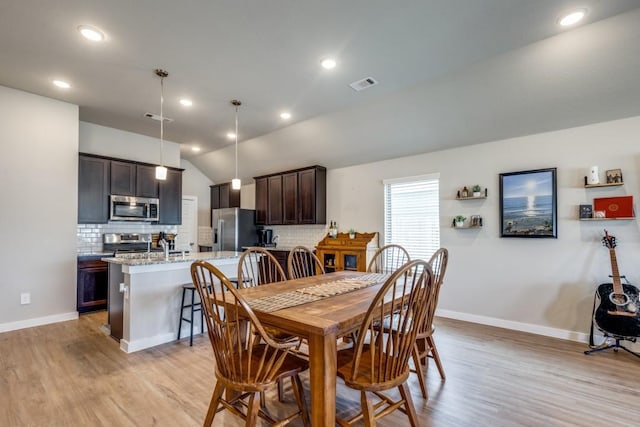 dining space with light wood-type flooring and lofted ceiling