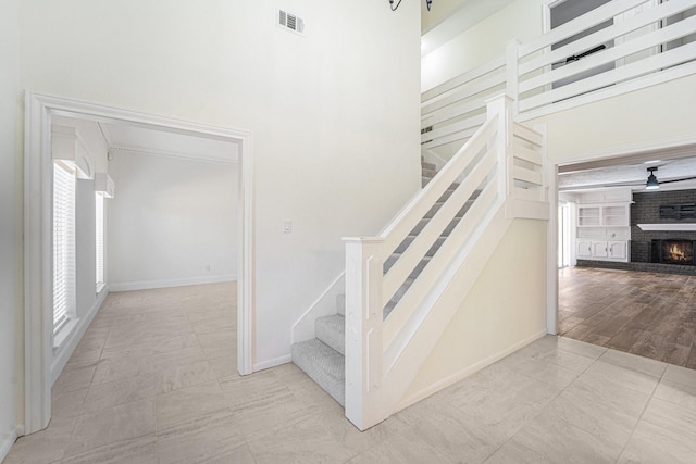 stairs featuring a fireplace, a high ceiling, tile patterned flooring, and built in features