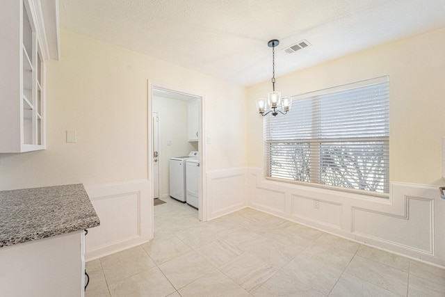 unfurnished dining area with a chandelier, light tile patterned floors, and washer and dryer