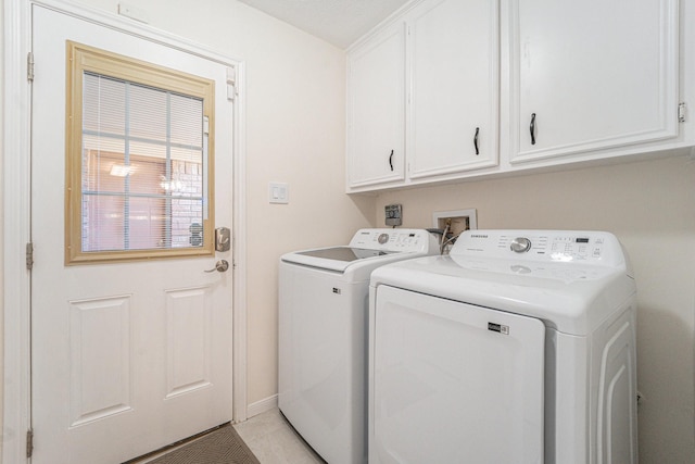 clothes washing area with light tile patterned flooring, cabinets, and separate washer and dryer