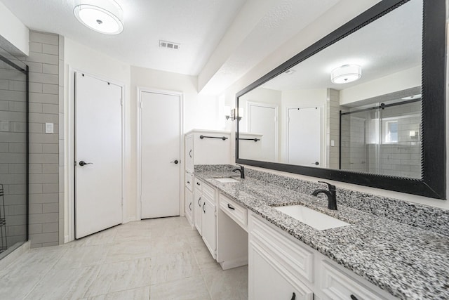 bathroom with a textured ceiling, vanity, and an enclosed shower