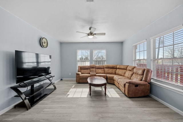 living room with ceiling fan, plenty of natural light, and light wood-type flooring