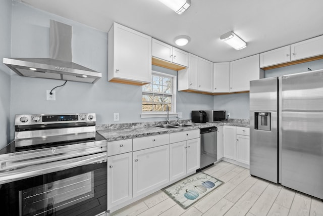 kitchen with light stone counters, wall chimney exhaust hood, stainless steel appliances, sink, and white cabinetry