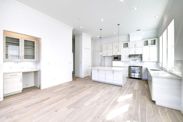 kitchen featuring sink, appliances with stainless steel finishes, tasteful backsplash, a kitchen island, and white cabinetry