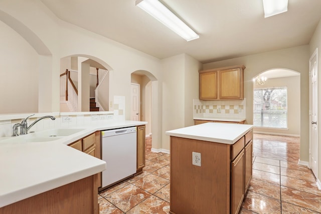 kitchen with white dishwasher, a kitchen island, sink, an inviting chandelier, and backsplash