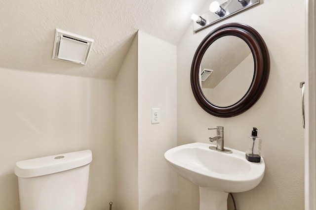 bathroom with sink, toilet, and lofted ceiling