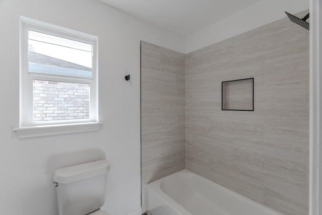 bathroom with tiled shower / bath combo and toilet