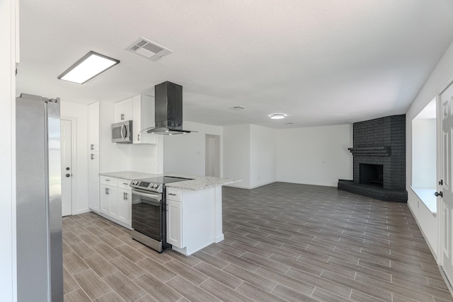 kitchen featuring white cabinets, appliances with stainless steel finishes, a brick fireplace, and exhaust hood