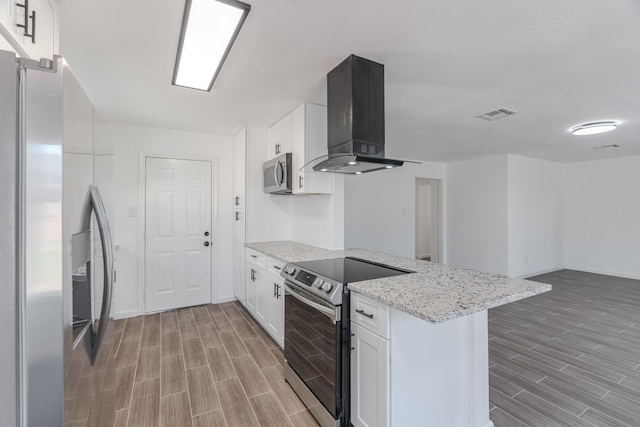 kitchen featuring white cabinets, wall chimney exhaust hood, kitchen peninsula, and appliances with stainless steel finishes