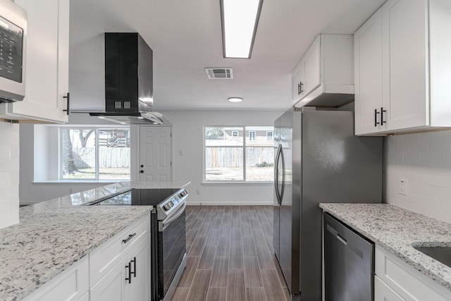 kitchen with light stone countertops, white cabinetry, extractor fan, decorative backsplash, and appliances with stainless steel finishes