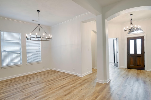 foyer entrance featuring light wood-type flooring, crown molding, and a chandelier