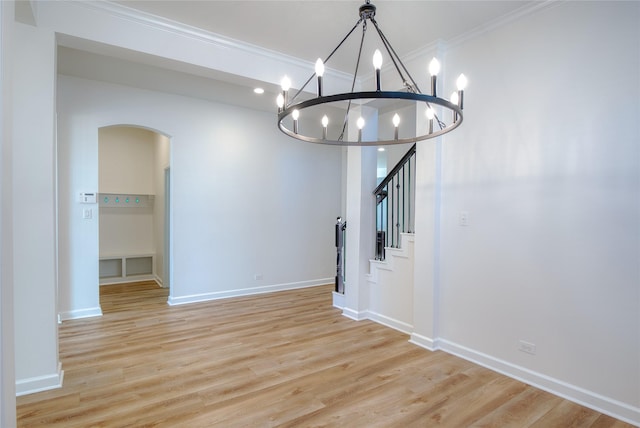 unfurnished dining area with a chandelier, light hardwood / wood-style floors, and ornamental molding